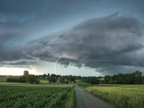 A thunderstorm passes over farm fields