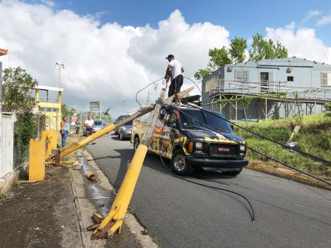 People attempt to remove broken power poles that landed on top a food truck in Puerto Rico after Hurricane Maria.