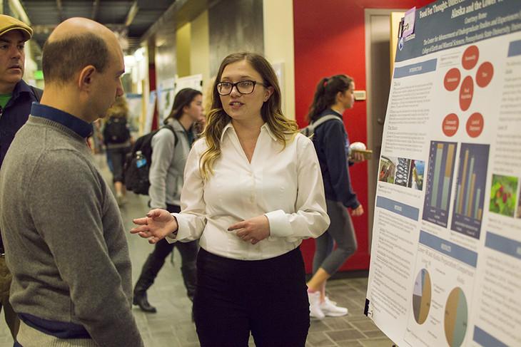 Courtney Rome speaking with an onlooker as she describes her poster